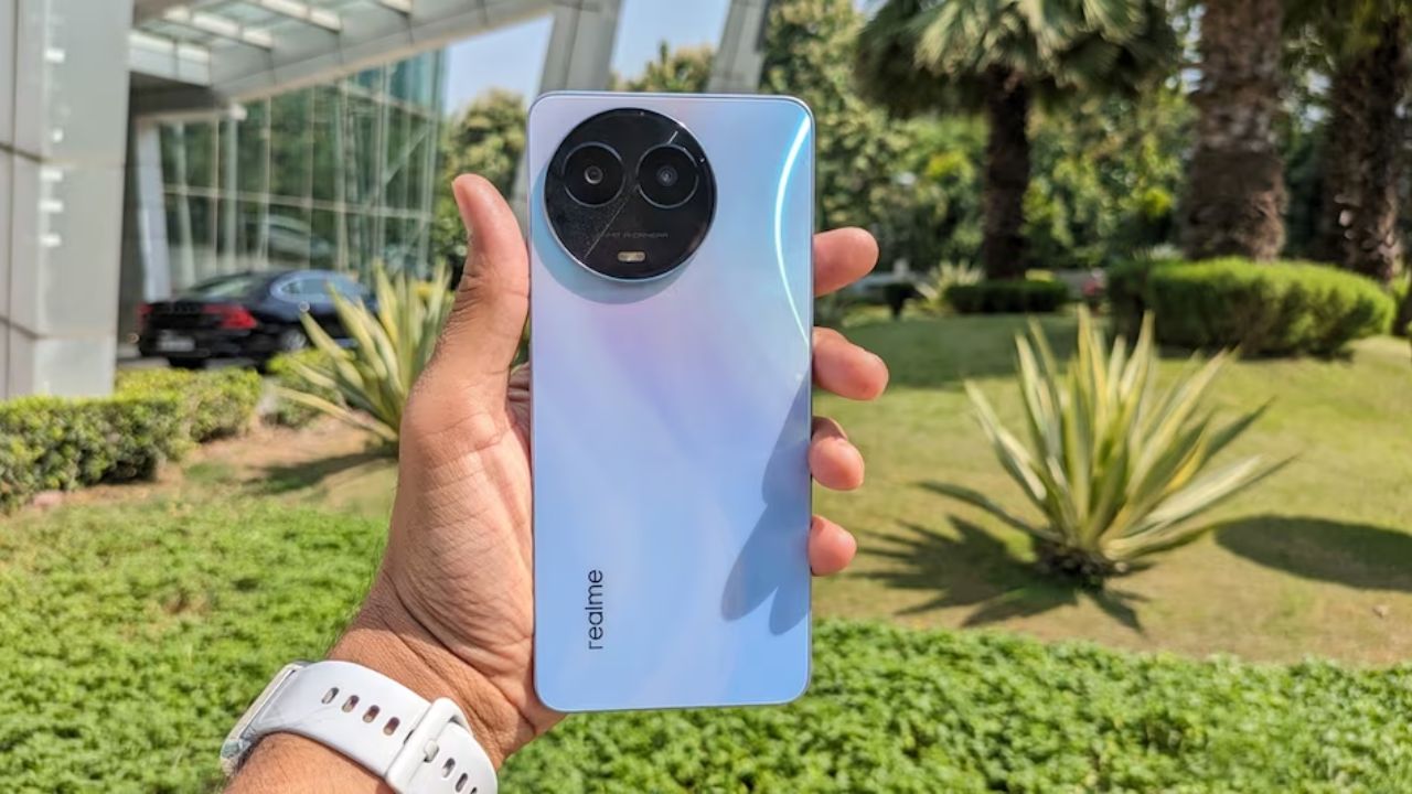realme 11x in hand in blue color infront of some trees in park