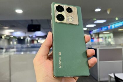 Infinix Note 40 5G in green color in hand infront of office in blurry background