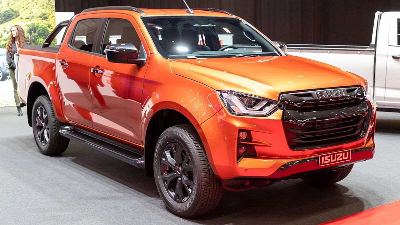 Here is image of orange colour Isuzu D-Max V-Cross Z Prestige which is placed in Showroom