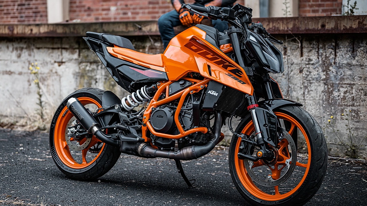 Here is image of Orange and black colour KTM Duke 390 Which is placed besides the road