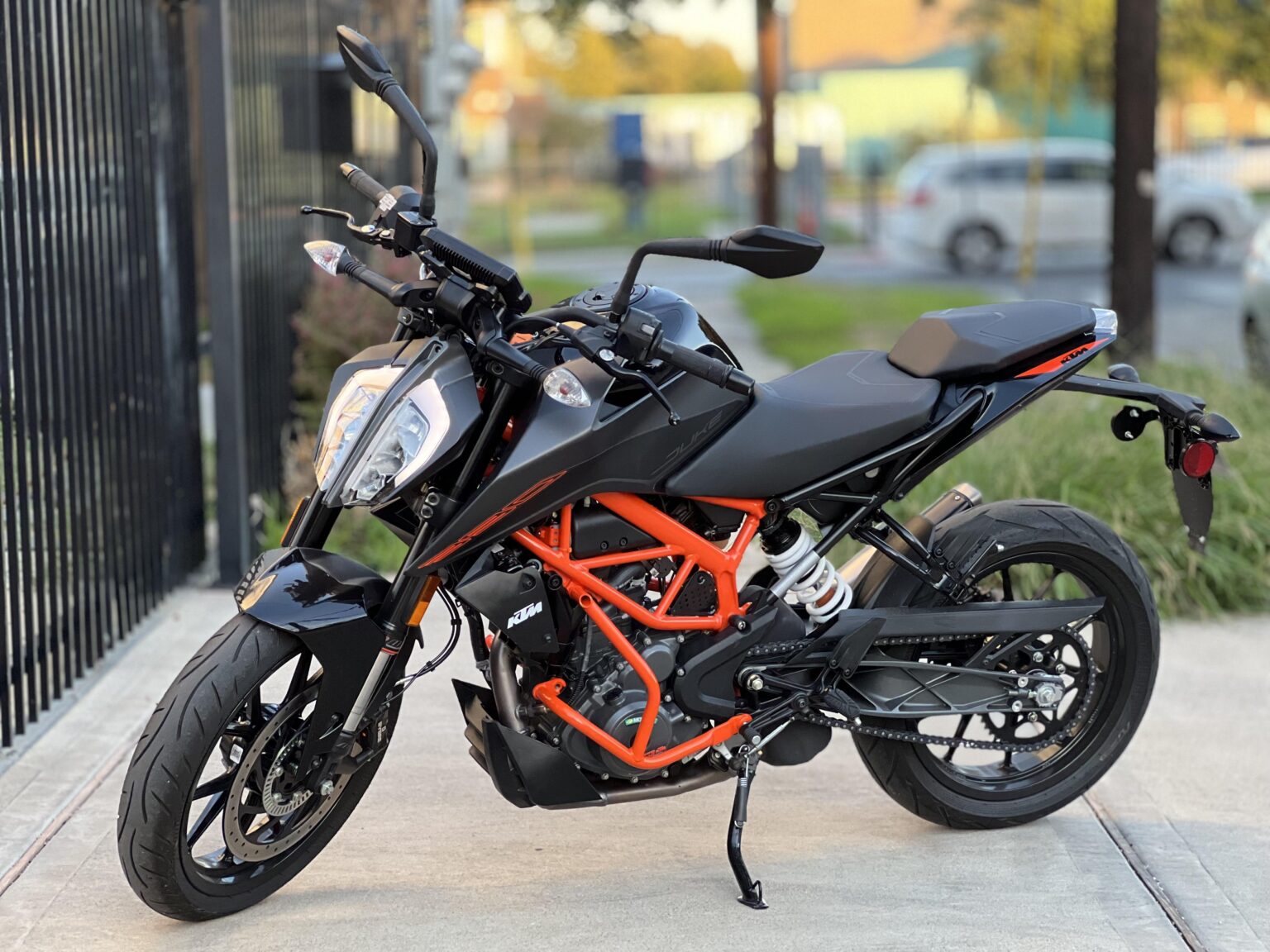 Here is image of black and red colour KTM Bike Which is placed in front of Gate of a building