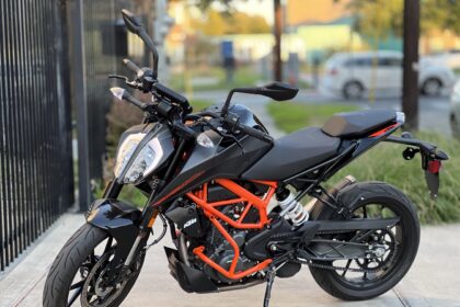 Here is image of black and red colour KTM Bike Which is placed in front of Gate of a building