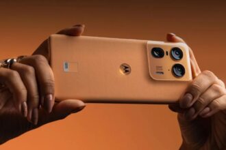 Motorola Edge 50 Ultra in in light orange color in hand infront of light orange background