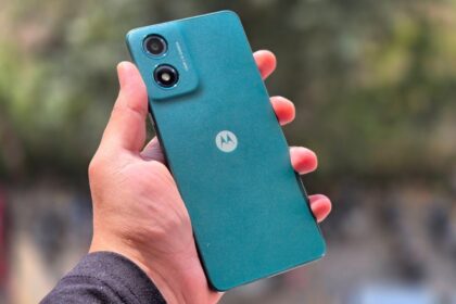 Motorola G04 in mint green color in a hand of man ifront of some trees