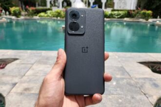OnePlus Nord 2t 5G in black color in hand infront of a swimming pool