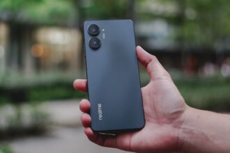 Realme 10 Pro 5G in black color in hand infront of bluryy background
