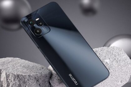 Realme C35 in black color standing infront of a stone on greyish background