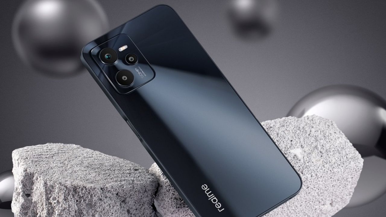 Realme C35 in black color standing infront of a stone on greyish background