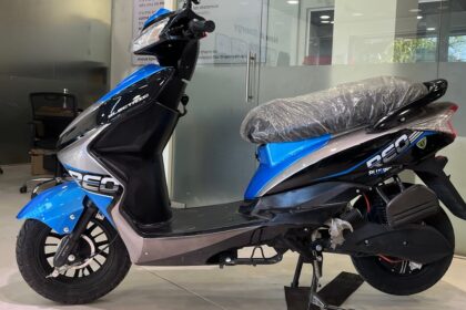 Here is image of black and blue colour Reo Li Plus Electric Scooter Which is placed in showroom