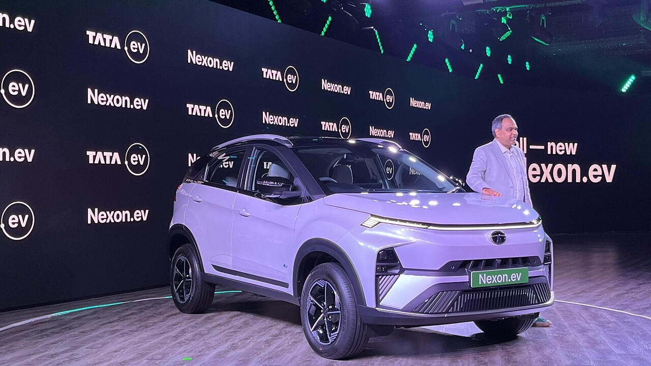 Here is image of a man standing behind a Tata Nexon EV car which is in white colour