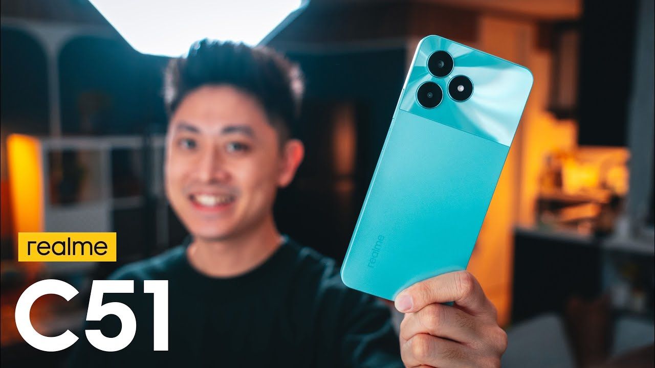 a man holding realme c51 in mint color in a studio
