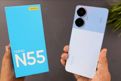 realme narzo n55 in blue color with box in hand infront of grey wall and a plant